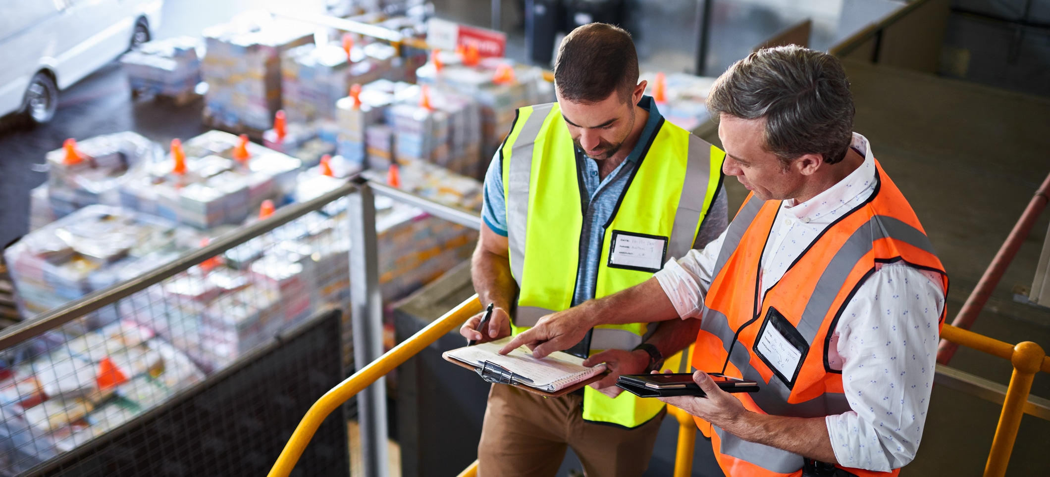 Two safety managers in an industrial environment looking at a clipboard.