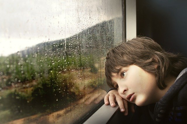 child looking out the window during lockdown.