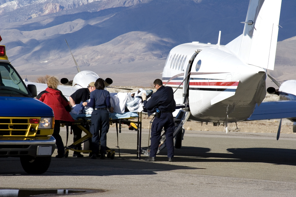 A medical team tranfers a patient from an ambulance to a waiting air ambulance.