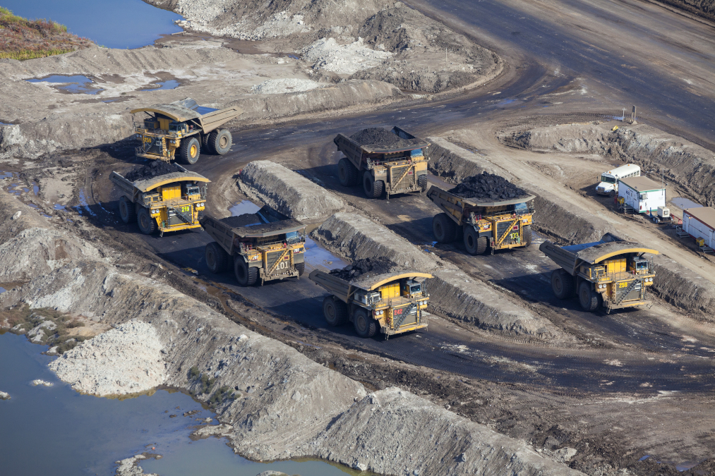 An aerial photo of large dump trucks parked at a mine staging area in Canada.